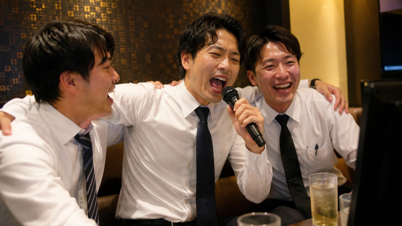 二次会カラオケで同僚と肩を組み熱唱する30代男性 ・画像